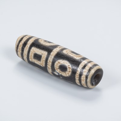 Lot 688 - AN TIBETAN AGATE ‘DZI’ BEAD, 19TH CENTUR OR EARLIER