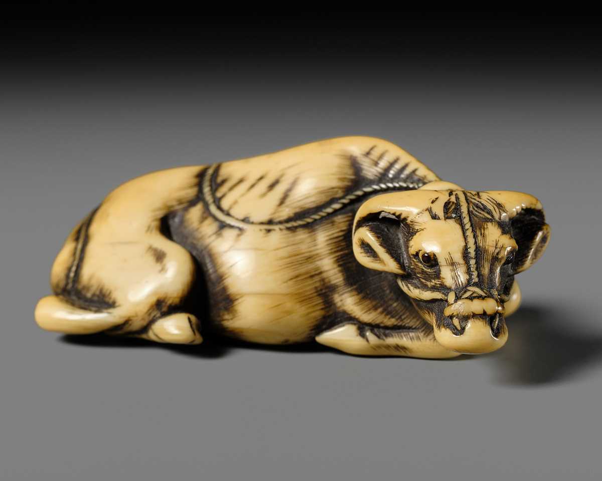 A GOOD KYOTO SCHOOL IVORY NETSUKE OF A RECUMBENT OX