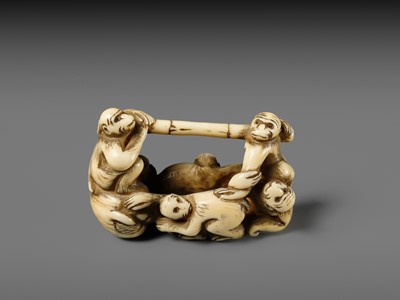 AN AMUSING IVORY NETSUKE OF A GROUP OF MONKEYS CARRYING A BAMBOO POLE