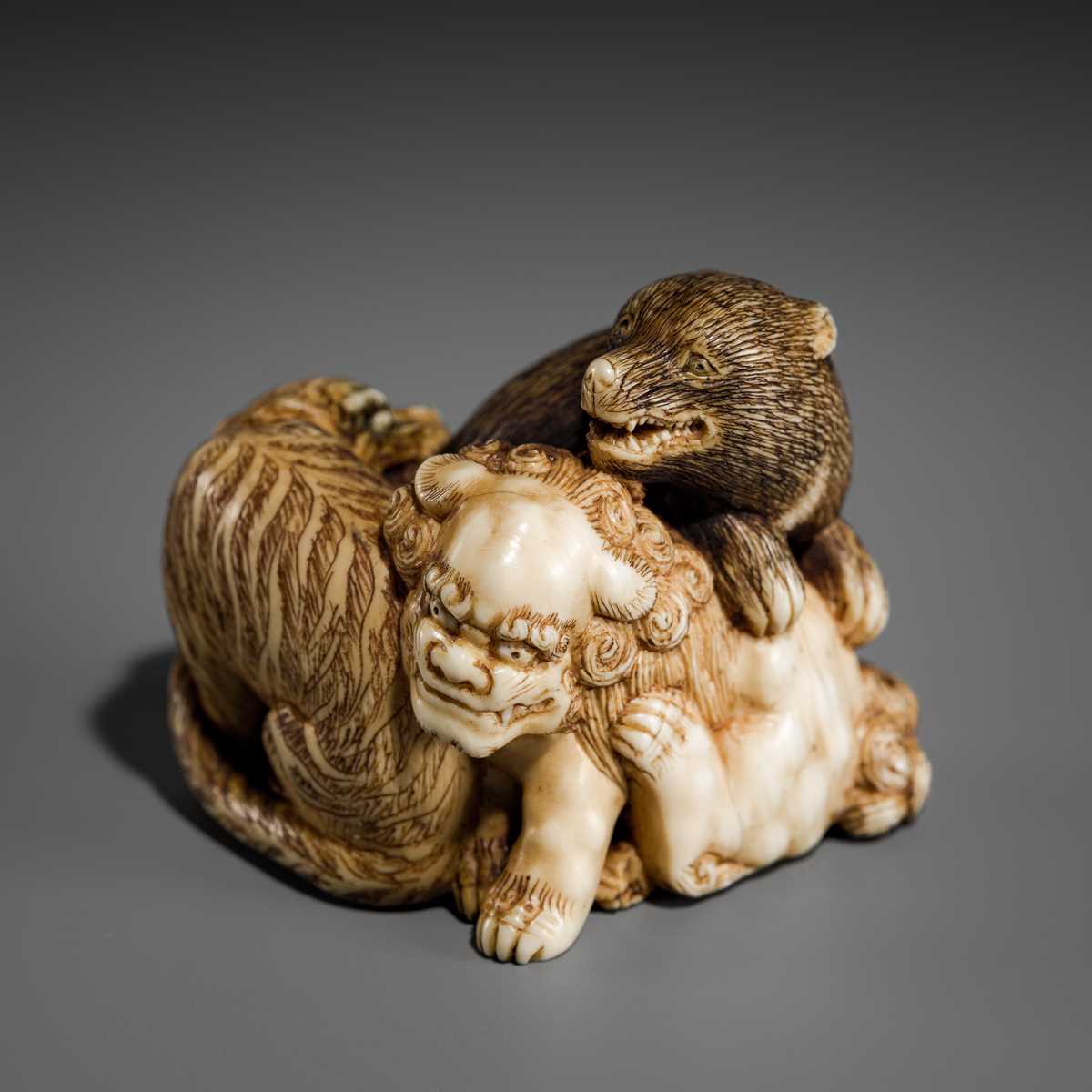 Lot 421 - TOMOCHIKA: AN IVORY NETSUKE OF A SHISHI, BEAR, AND TIGER