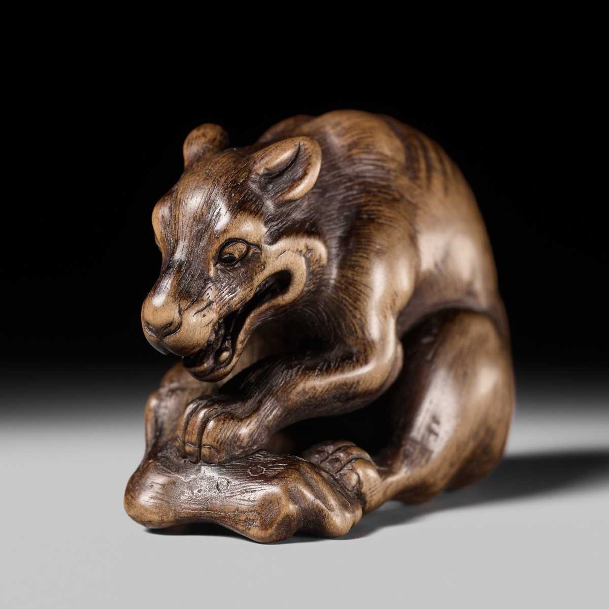 Lot 146 - A FINE WOOD NETSUKE OF A WOLF WITH HAUNCH OF VENISON, ATTRIBUTED TO OKATOMO