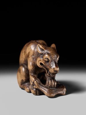 Lot 146 - A FINE WOOD NETSUKE OF A WOLF WITH HAUNCH OF VENISON, ATTRIBUTED TO OKATOMO