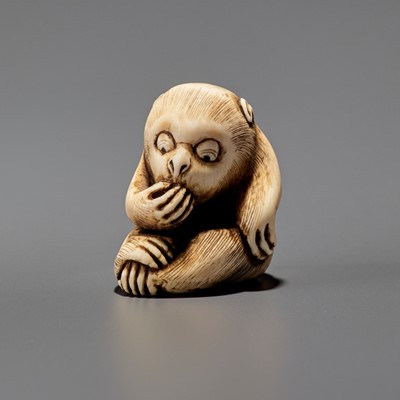 Lot 1539 - AN IVORY NETSUKE OF A MONKEY EATING A FRUIT