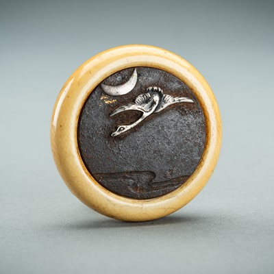 Lot 1713 - AN IVORY AND IRON KAGAMIBUTA NETSUKE DEPICTING A CRANE AND THE MOON, EDO