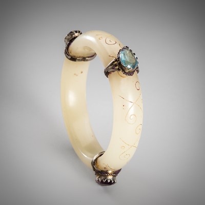 Lot 1345 - A PALE CELADON JADE BANGLE WITH THREE SILVERED RINGS, LATE 19TH TO 20TH CENTURY