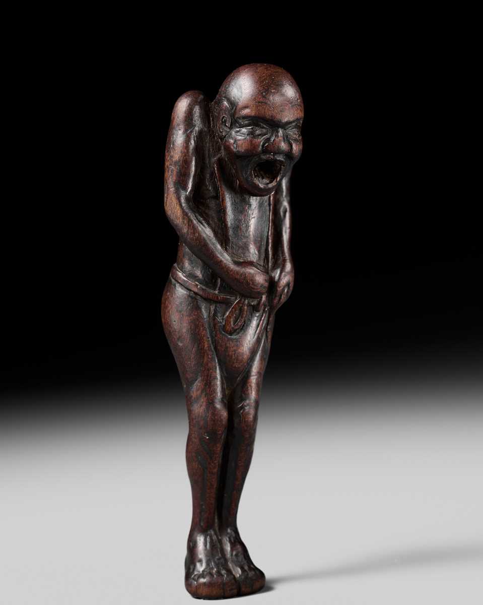 A TALL WOOD NETSUKE OF A MAN TYING HIS FUNDOSHI (LOINCLOTH), ATTRIBUTED TO AWATAGUCHI