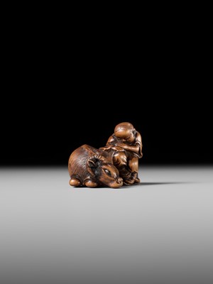A FINE WOOD NETSUKE OF A HERDBOY SLEEPING ON AN OX