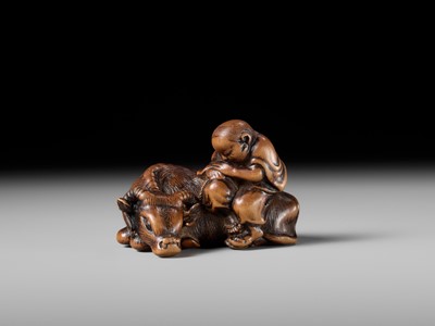 A FINE WOOD NETSUKE OF A HERDBOY SLEEPING ON AN OX