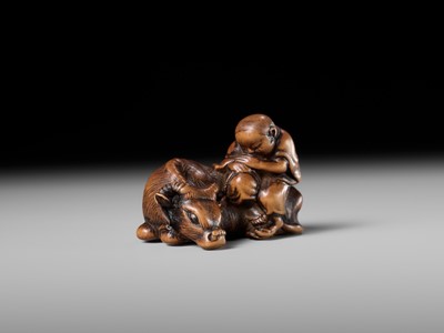 A FINE WOOD NETSUKE OF A HERDBOY SLEEPING ON AN OX