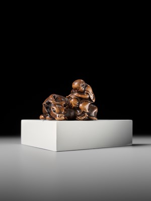 A FINE WOOD NETSUKE OF A HERDBOY SLEEPING ON AN OX