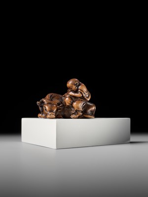 A FINE WOOD NETSUKE OF A HERDBOY SLEEPING ON AN OX