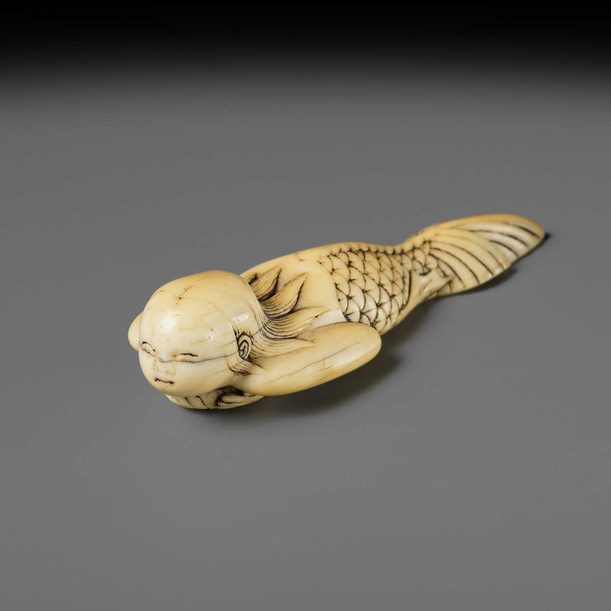 Lot 114 - A FINE IVORY NETSUKE OF A SWIMMING NINGYO (MERMAID)