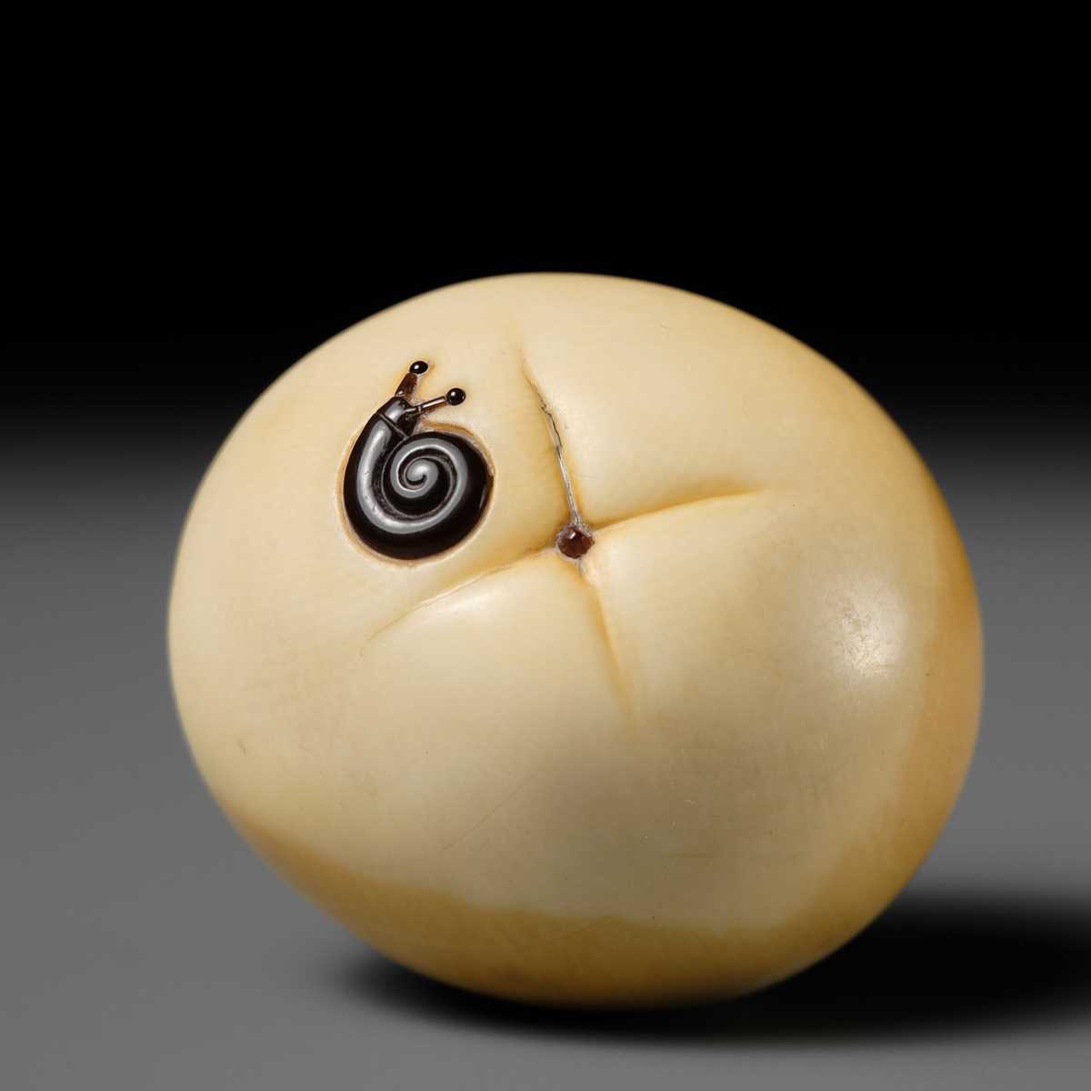 UNSHO HAKURYU: A FINE IVORY NETSUKE OF A PERSIMMON WITH INLAID SNAIL
