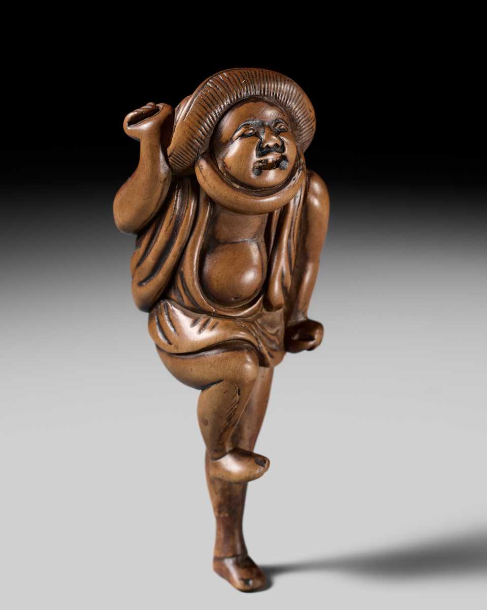 Lot 96 - A SUPERB WOOD NETSUKE OF A DANCING KUMOSUKE (ROAD PORTER)