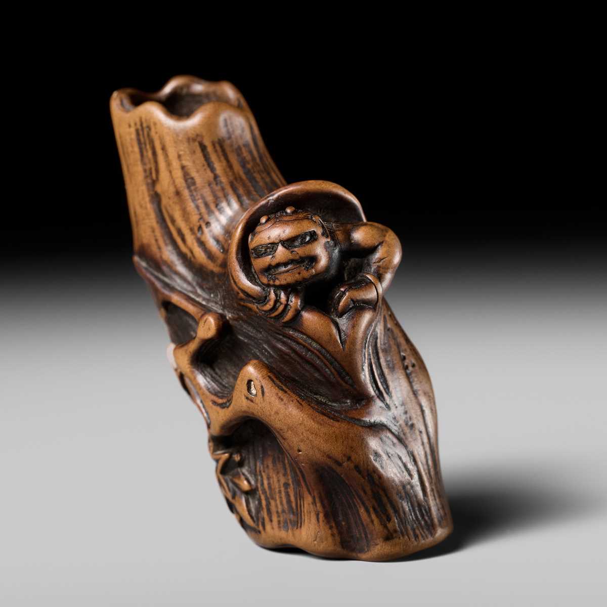 Lot 134 - MASAKAZU: A RARE WOOD NETSUKE OF AN ONI HIDING IN A TREE STUMP
