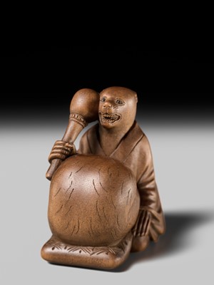 Lot 398 - SUKETADA: AN AMUSING WOOD NETSUKE OF A TANUKI BEATING A MOKUGYO