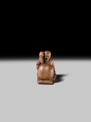 Lot 398 - SUKETADA: AN AMUSING WOOD NETSUKE OF A TANUKI BEATING A MOKUGYO