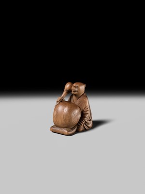 Lot 398 - SUKETADA: AN AMUSING WOOD NETSUKE OF A TANUKI BEATING A MOKUGYO