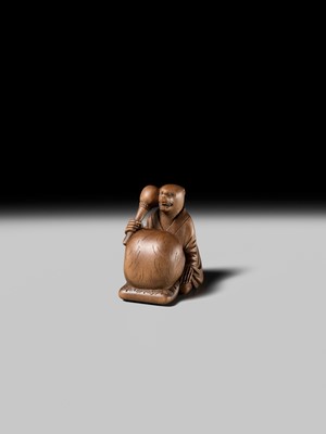 Lot 398 - SUKETADA: AN AMUSING WOOD NETSUKE OF A TANUKI BEATING A MOKUGYO