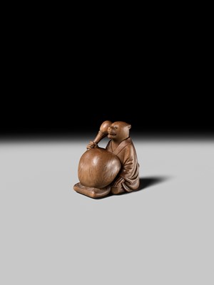 Lot 398 - SUKETADA: AN AMUSING WOOD NETSUKE OF A TANUKI BEATING A MOKUGYO