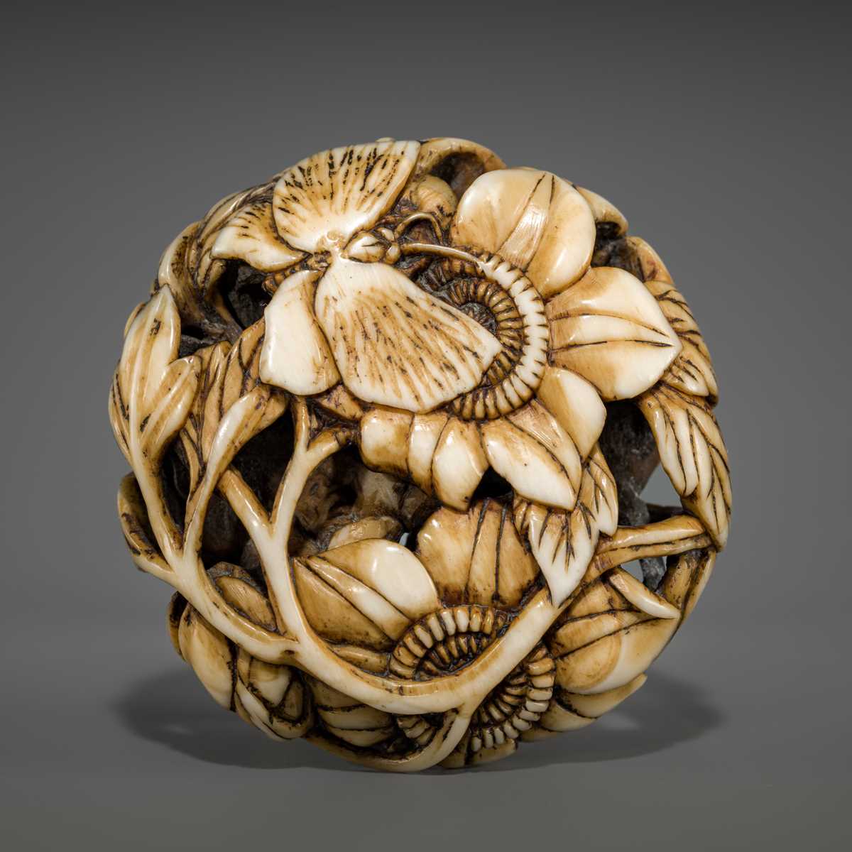 Lot 473 - A FINE WALRUS TUSK RYUSA MANJU NETSUKE OF BUTTERFLIES AND SUNFLOWERS