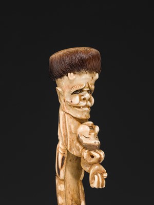 Lot 76 - AN ANTLER KISERUZUTSU (PIPE CASE) OF AN ONI WITH AN OKAME MASK