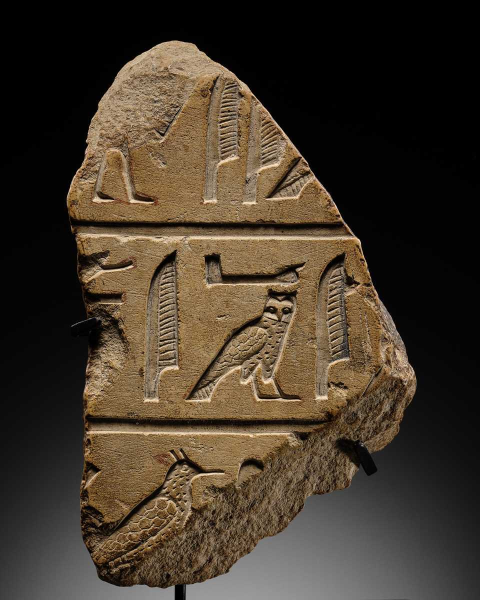 Lot 23 - A LIMESTONE RELIEF FRAGMENT WITH HIEROGLYPHIC INSCRIPTION, OLD KINGDOM OR ARCHAIZING LATE PERIOD