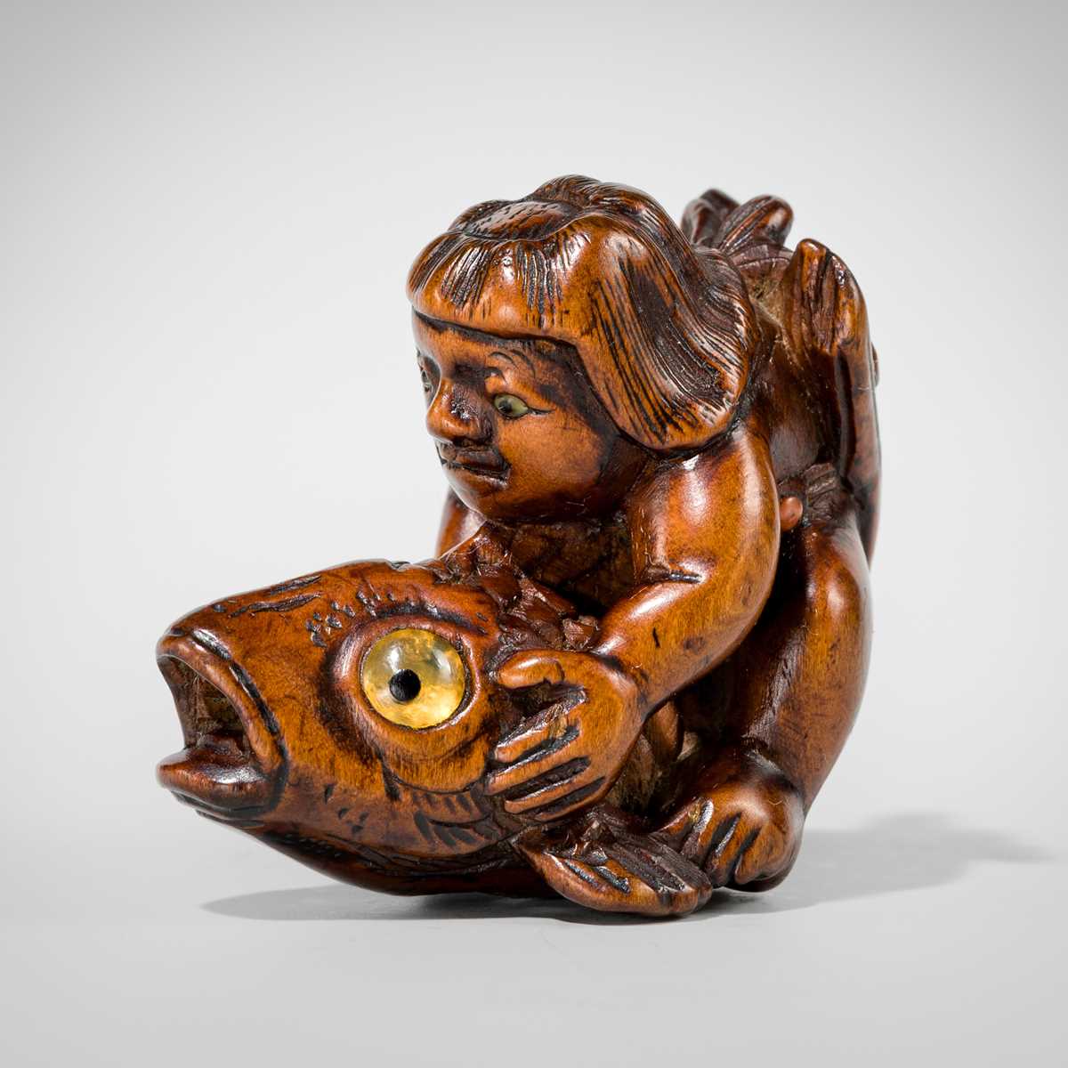 Lot 426 - AN AMUSING INLAID WOOD NETSUKE OF ONIWAKAMARU STRUGGLING WITH THE GIANT CARP