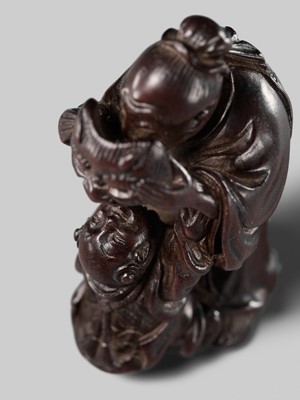 Lot 132 - HIDEMASA: A WOOD NETSUKE DEPICTING A CHINESE MAN SCARING A KARAKO