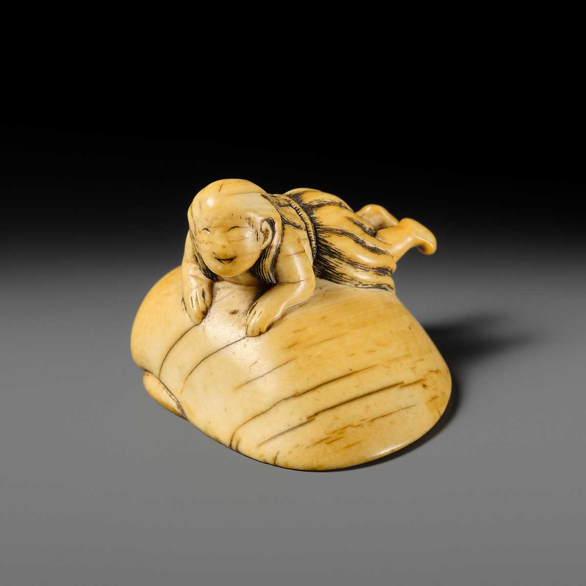 AN IVORY NETSUKE OF A FISHERGIRL (AMA) ON A LARGE CLAM