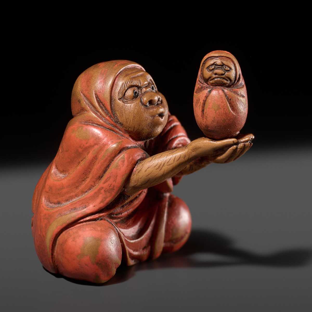 Lot 169 - AN AMUSING LACQUERED WOOD NETSUKE OF DARUMA BALANCING A DARUMA DOLL, ATTRIBUTED TO ANRAKU