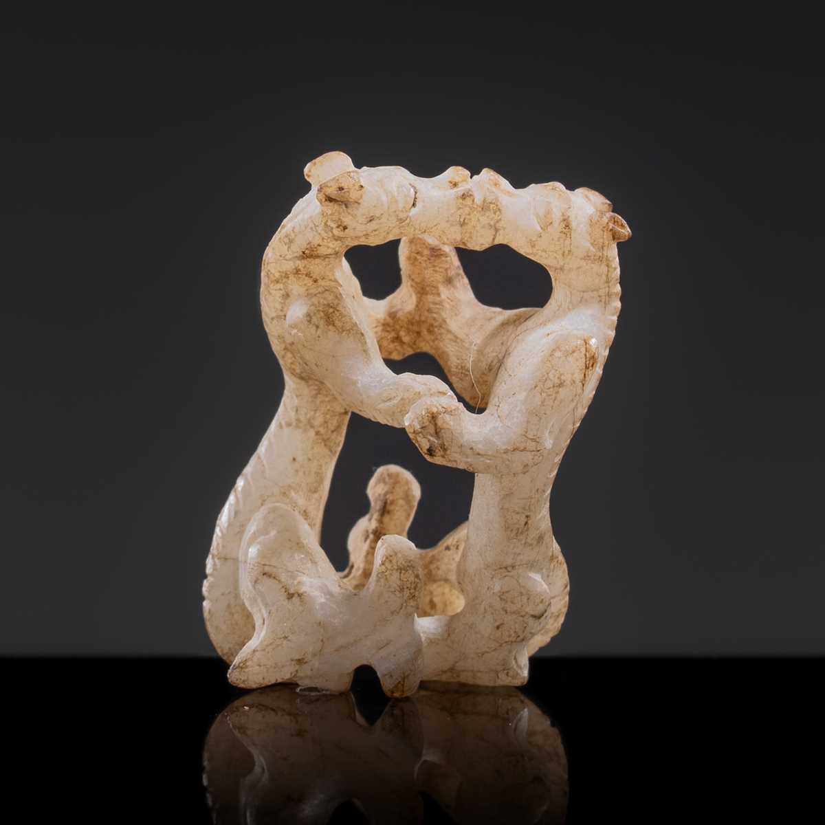 Lot 19 - A RETICULATED WHITE JADE MINIATURE PENDANT OF TWO FROLICKING TIGERS, WARRING STATES OR WESTERN HAN DYNASTY