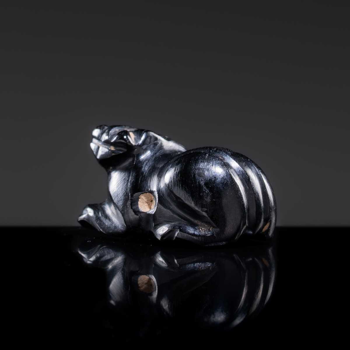 Lot 23 - A BLACK GIT BEAD IN THE FORM OF A RECUMBENT LION, HAN DYNASTY