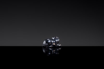 Lot 23 - A BLACK GIT BEAD IN THE FORM OF A RECUMBENT LION, HAN DYNASTY