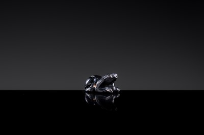 Lot 23 - A BLACK GIT BEAD IN THE FORM OF A RECUMBENT LION, HAN DYNASTY