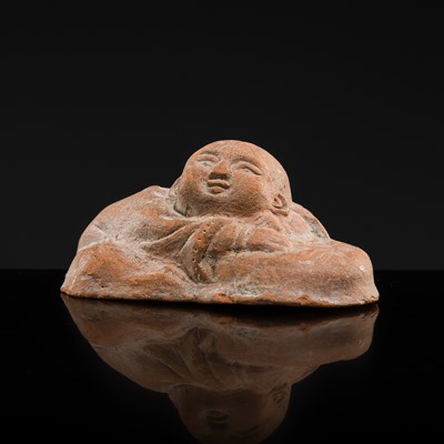 Lot 95 - AN UNGLAZED RED EARTHENWARE FIGURE OF A RECLINING BOY, SONG DYNASTY