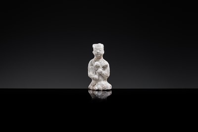 A SMALL WHITE GLAZED DINGYAO FIGURE OF A SEATED BOY WITH LOTUS FLOWERS, NORTHERN SONG DYNASTY