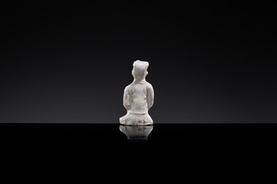 A SMALL WHITE GLAZED DINGYAO FIGURE OF A SEATED BOY WITH LOTUS FLOWERS, NORTHERN SONG DYNASTY