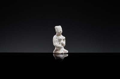A SMALL WHITE GLAZED DINGYAO FIGURE OF A SEATED BOY WITH LOTUS FLOWERS, NORTHERN SONG DYNASTY