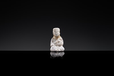 A SMALL WHITE GLAZED DINGYAO FIGURE OF A SEATED BOY HOLDING A DOLL, NORTHERN SONG DYNASTY