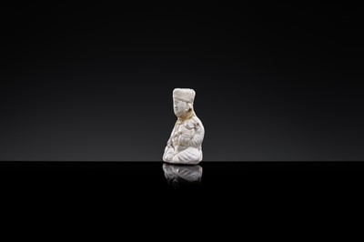A SMALL WHITE GLAZED DINGYAO FIGURE OF A SEATED BOY HOLDING A DOLL, NORTHERN SONG DYNASTY