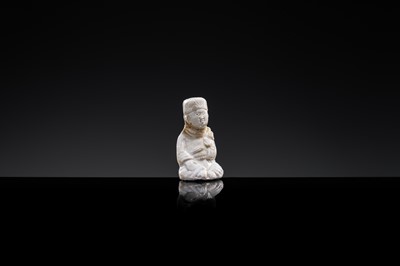 A SMALL WHITE GLAZED DINGYAO FIGURE OF A SEATED BOY HOLDING A DOLL, NORTHERN SONG DYNASTY