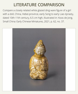 A SMALL WHITE GLAZED DINGYAO FIGURE OF A SEATED BOY HOLDING A DOLL, NORTHERN SONG DYNASTY