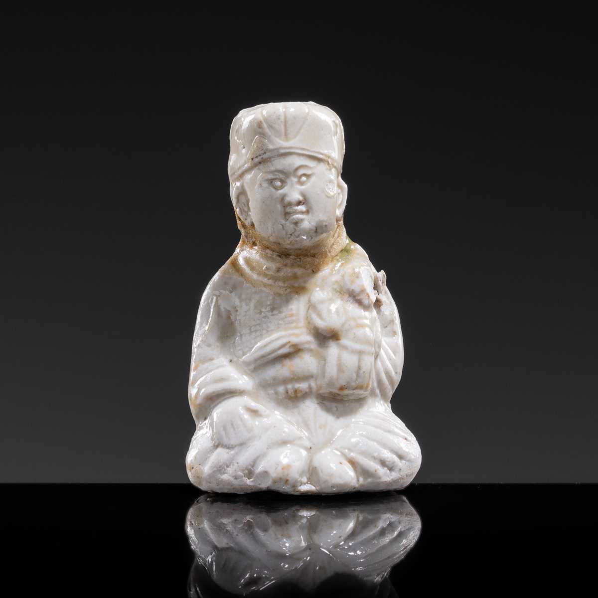A SMALL WHITE GLAZED DINGYAO FIGURE OF A SEATED BOY HOLDING A DOLL, NORTHERN SONG DYNASTY