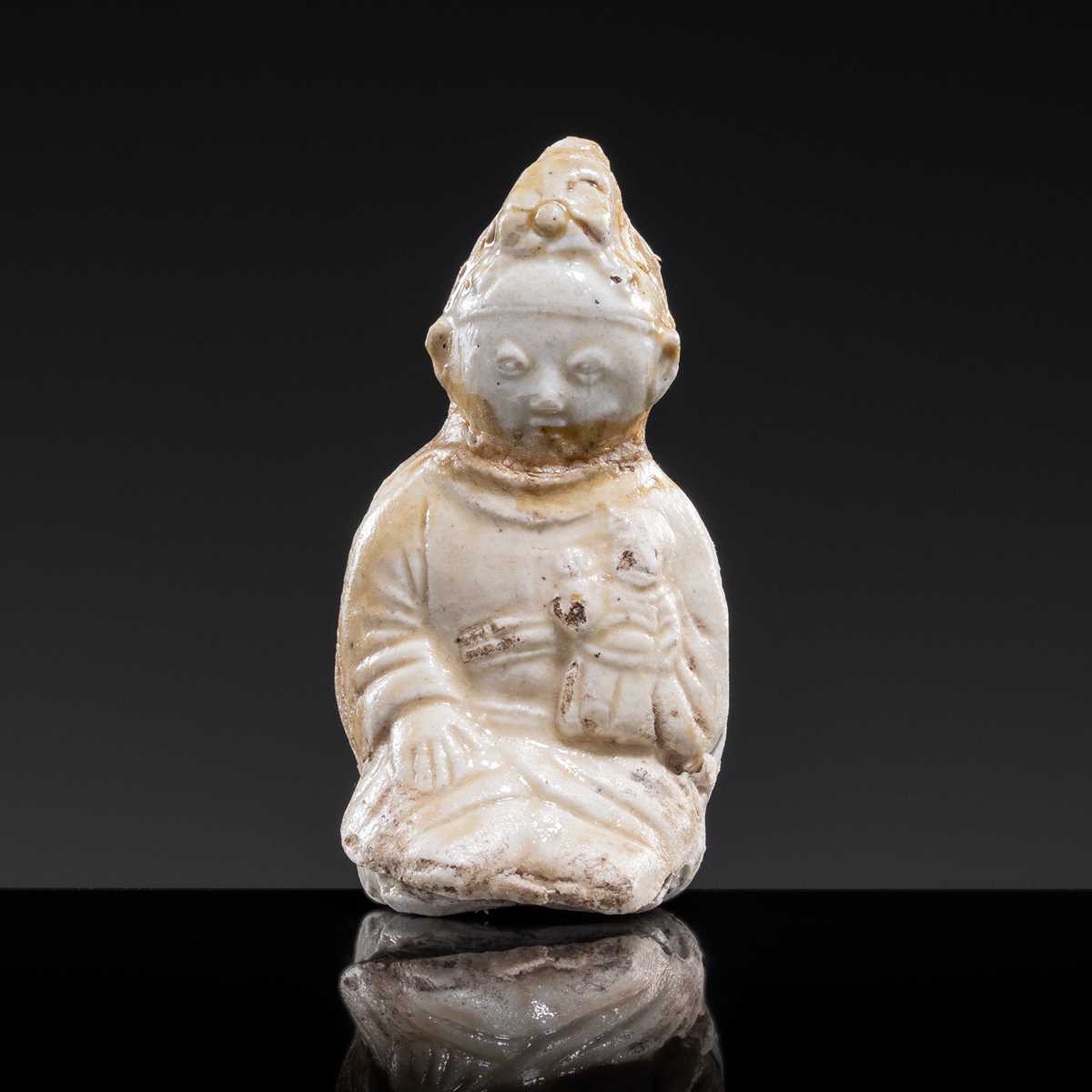 Lot 59 - A SMALL WHITE GLAZED DINGYAO FIGURE OF A SEATED GIRL HOLDING A DOLL, EARLY SONG TO EARLY LIAO DYNASTY