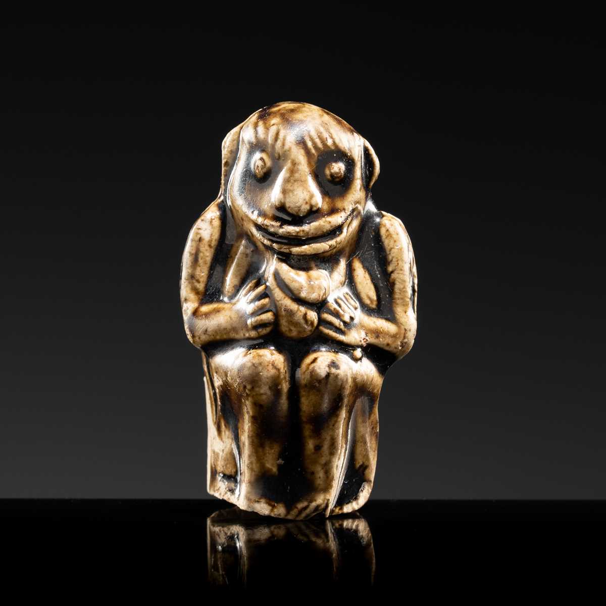 A BROWN GLAZED STONEWARE WHISTLE IN THE FORM OF A MONKEY HOLDING A PEACH, SONG TO JIN DYNASTY