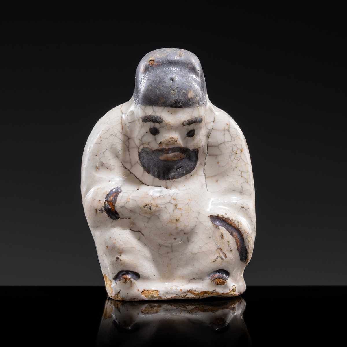 A WHITE AND DARK BROWN GLAZED STONEWARE FIGURE OF AN OFFICIAL, YUAN DYNASTY