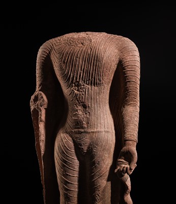 AN ICONIC RED SANDSTONE TORSO OF THE BUDDHA, GUPTA PERIOD, MATHURA, 3RD-5TH CENTURY