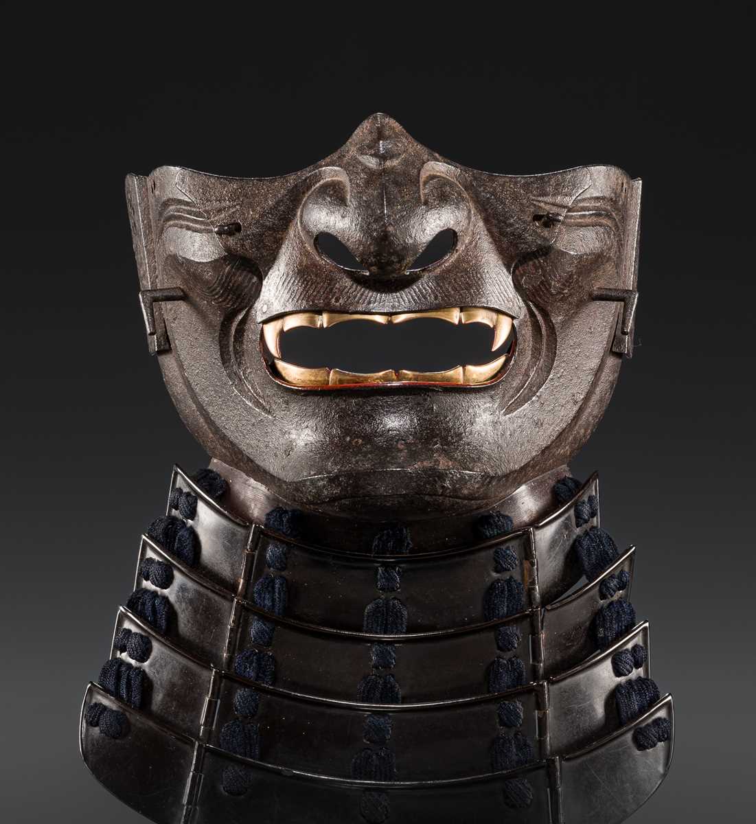 Lot 88 - A LACQUERED IRON ‘FANGED’ RESSEI MENPO