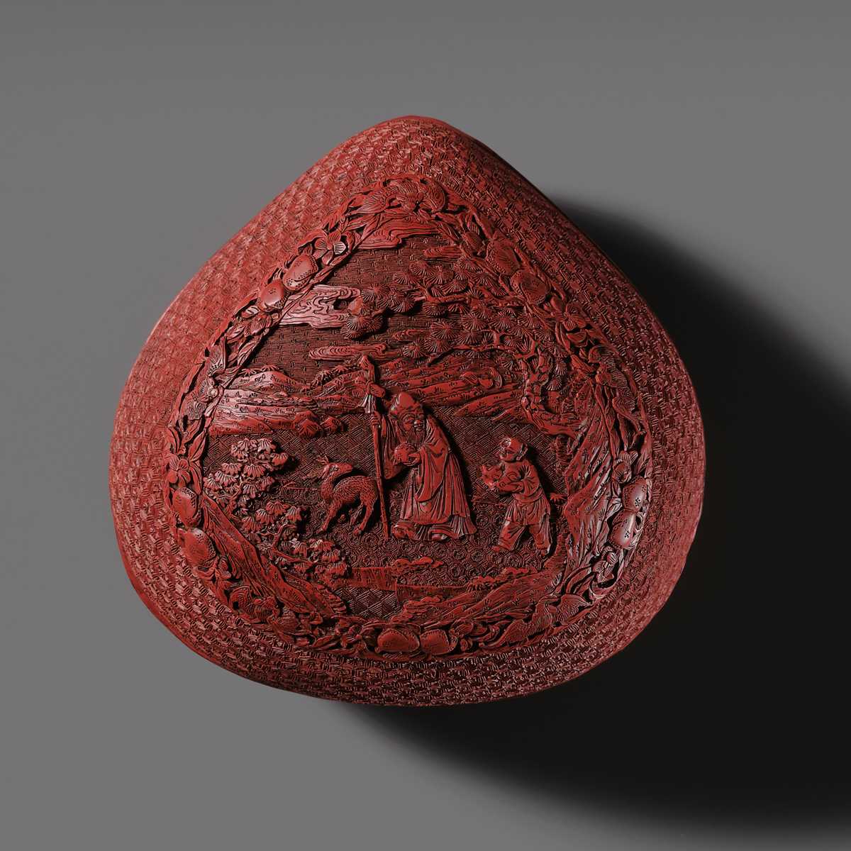 Lot 115 - A CINNABAR LACQUER PEACH-FORM BOX AND COVER DEPICTING SHOULAO, 18TH CENTURY